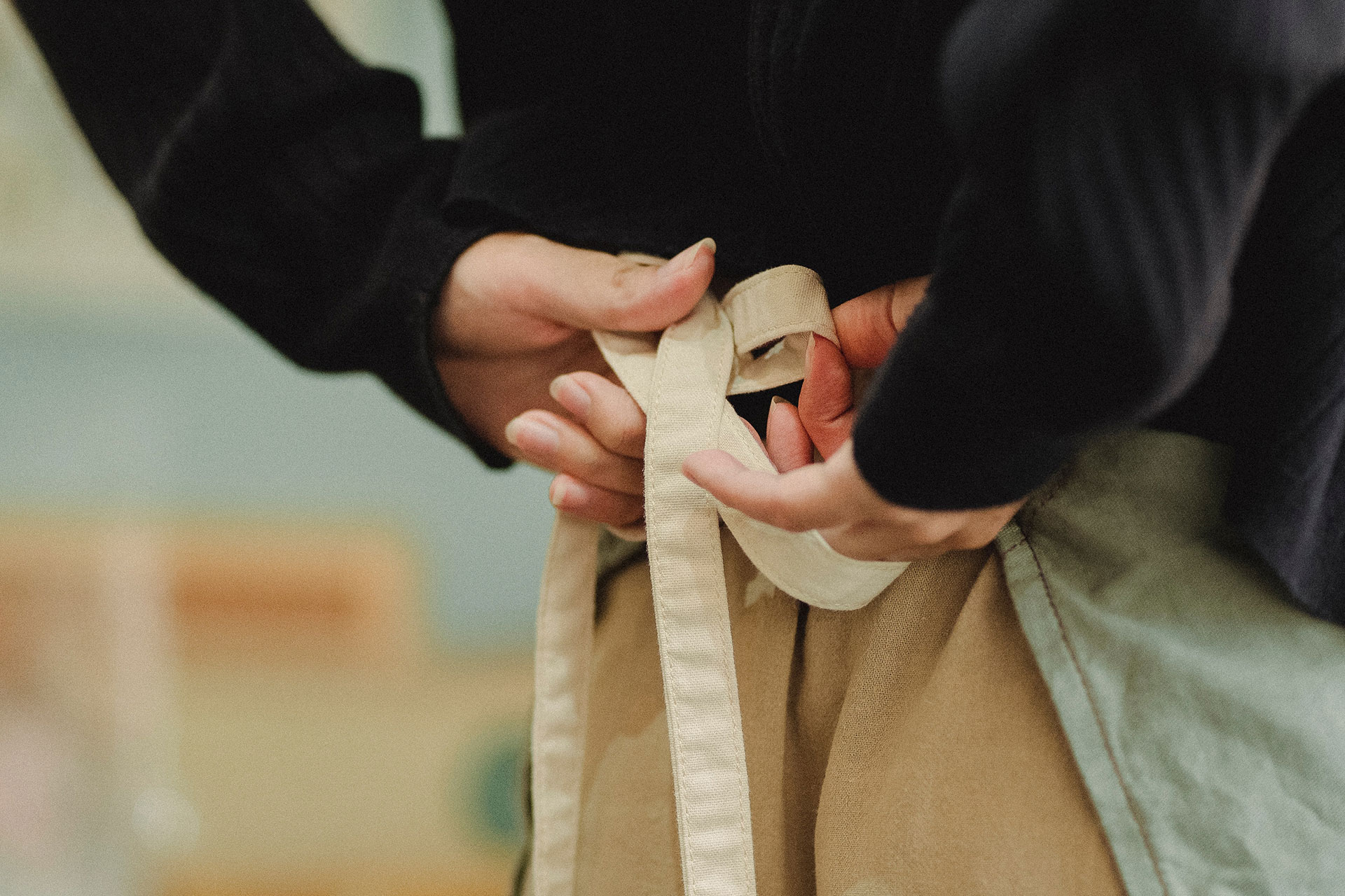 Eine Frau bindet sich eine Küchenschürze hinter dem Rücken selbst zu